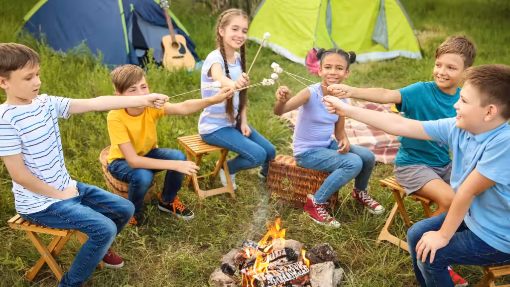 Children gathered around a campfire at an American-style summer camps UK