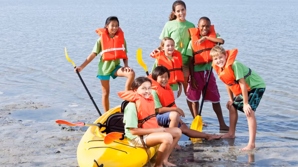 A diverse group of children in life jackets with a camp counselor at summer camps in England for international students